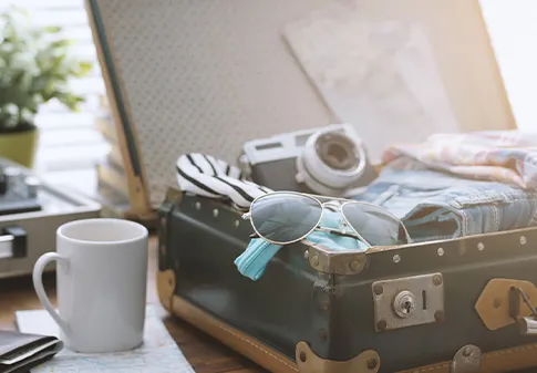 Open suitcase with camera sunglasses and clothing inside